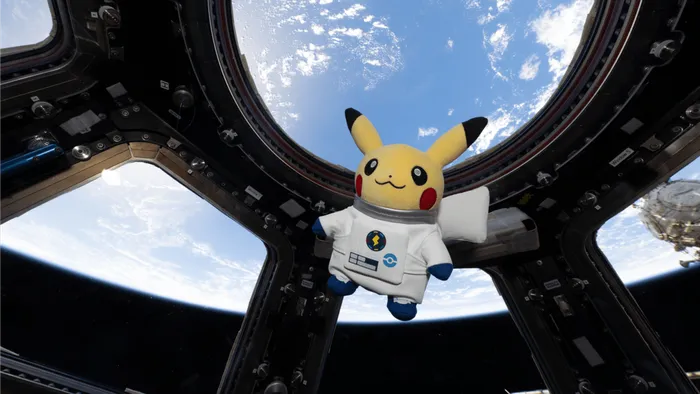 The Astronaut Pikachu plush floating in the ISS Cupola with Earth in the windows
